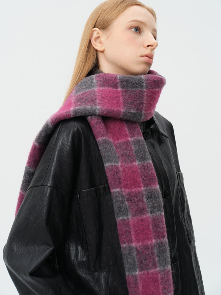 Close-up of a woman wearing a pink and grey plaid scarf wrapped around her neck.