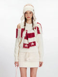 Full body shot of a model in a cream knit outfit, including a sweater, skirt, hat, and scarf.