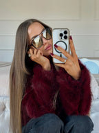 Woman taking a selfie in a burgundy faux fur jacket and sunglasses.