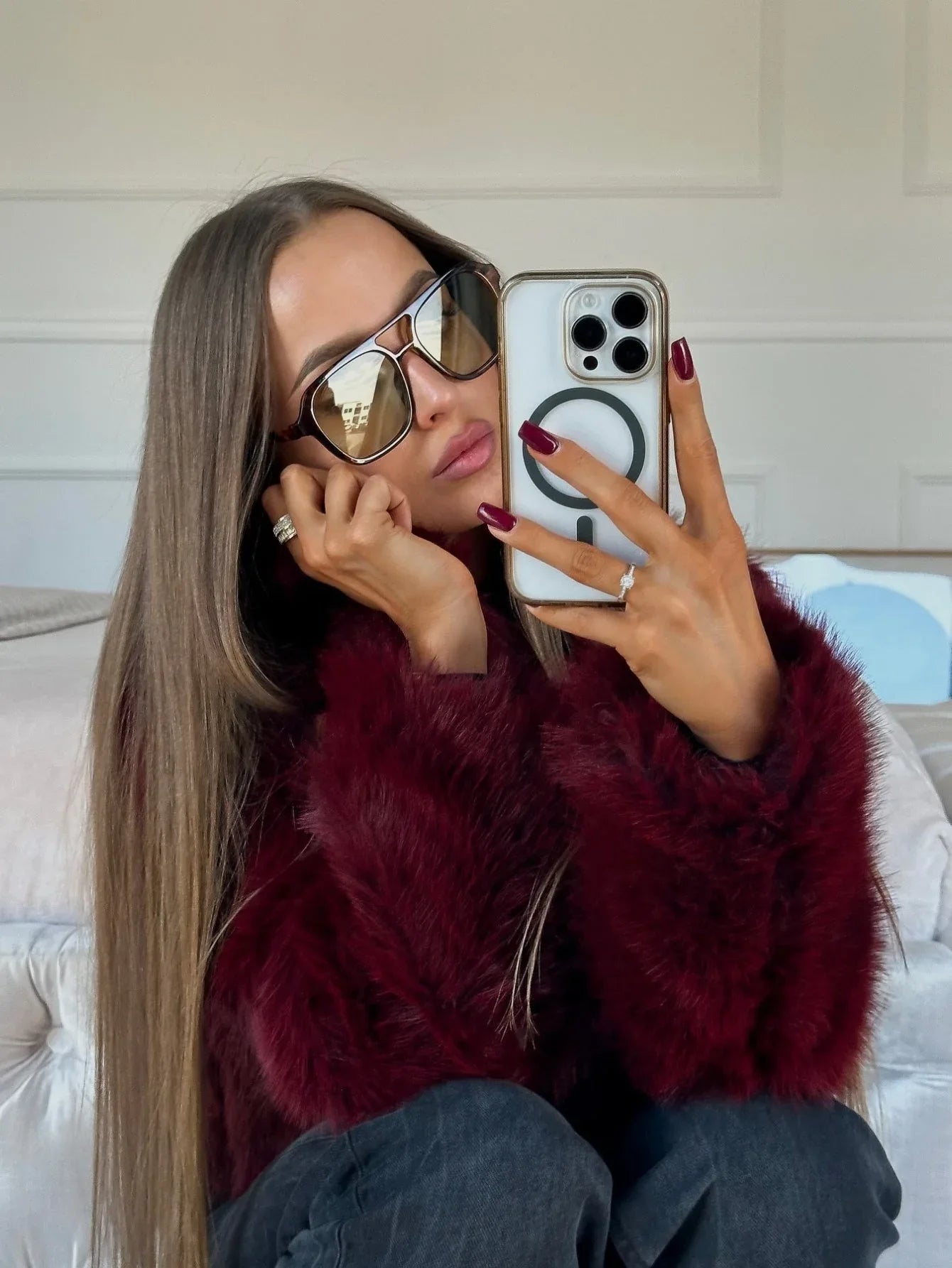 Woman taking a selfie in a burgundy faux fur jacket and sunglasses.