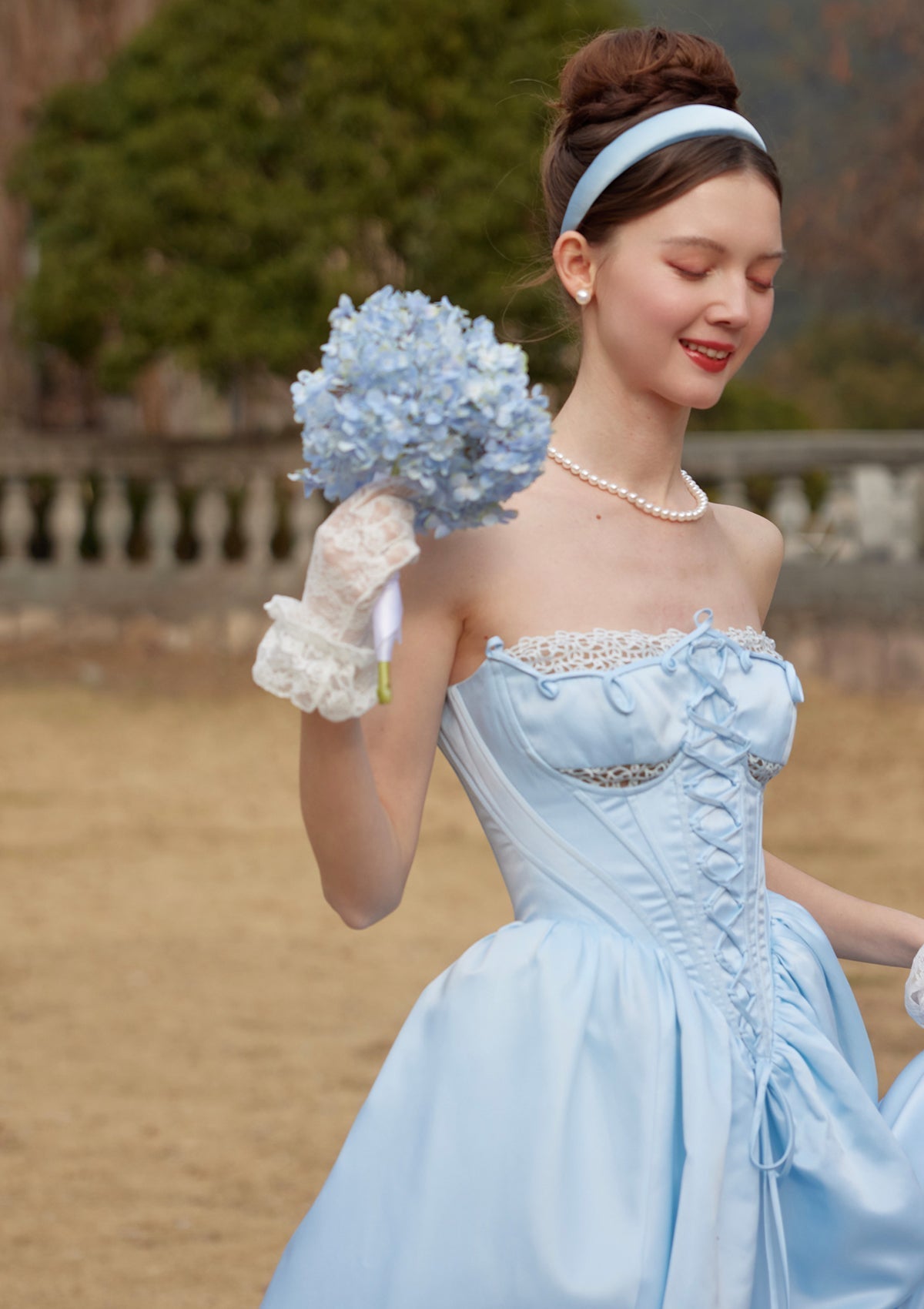 Close-up of the bodice of a light blue strapless gown showing lace trim and corset lacing.