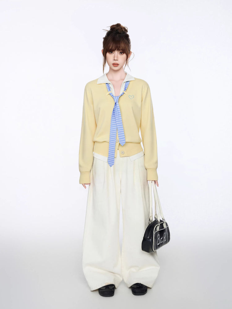 Woman posing with hands in pockets wearing a yellow cardigan and white pants