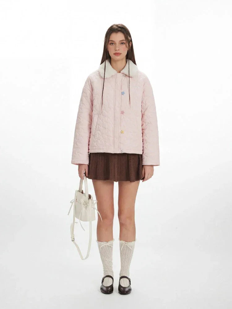 Woman wearing a pink quilted jacket with a white faux fur collar and star buttons.