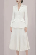 Front view of a woman in a white blazer and pleated skirt.