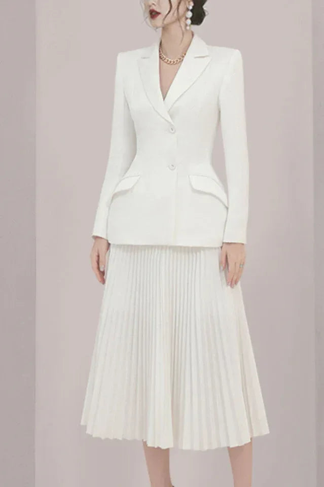 Front view of a woman in a white blazer and pleated skirt.