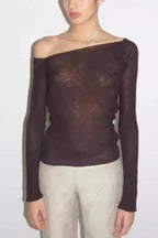 Model wearing a dark brown sheer long-sleeve top with an asymmetrical neckline and an open back.