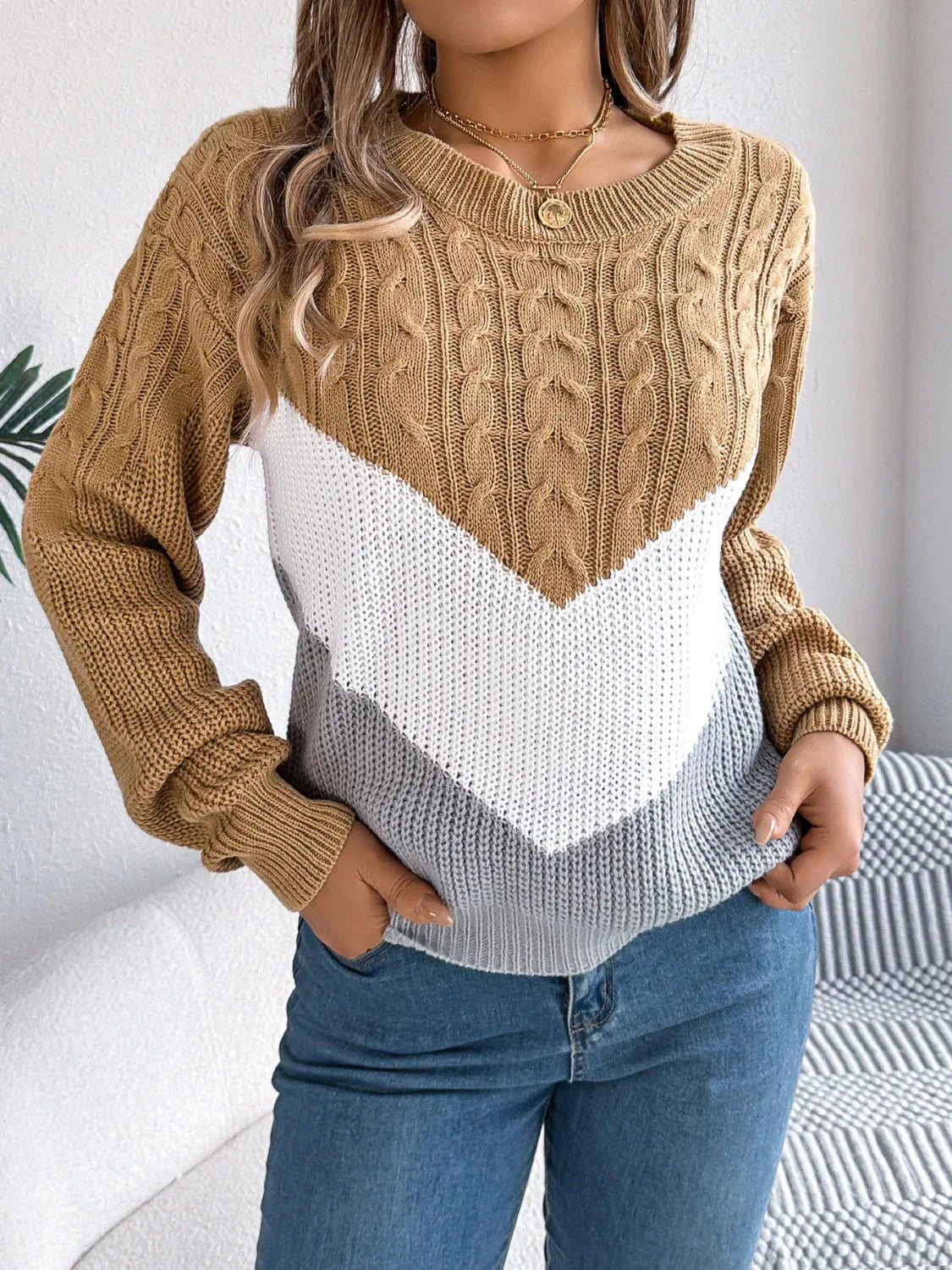 Front detail of a woman in a tan, white, and grey chevron color block knit sweater