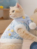Side profile of a cat adorned in a blue and white striped pet outfit featuring star embellishments.