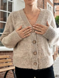 Detail of the button closure on a beige v-neck cardigan
