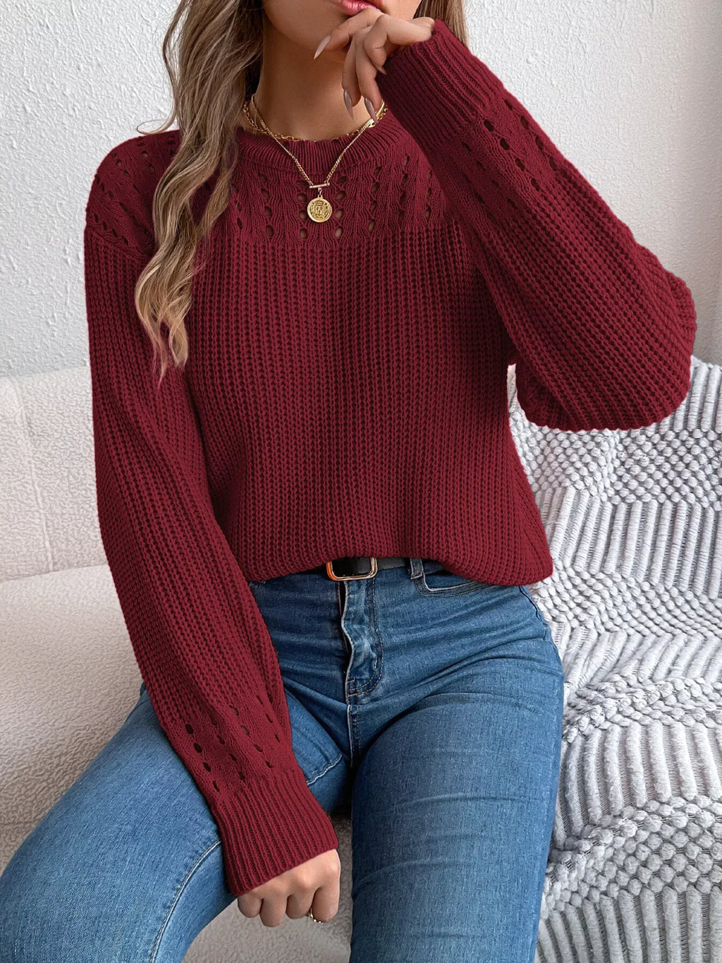Close-up of a woman wearing a burgundy knit sweater with crew neck and long sleeves.