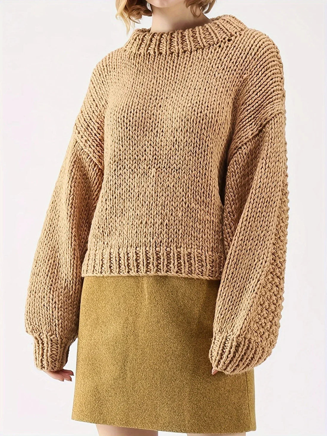 Woman wearing a tan chunky knit sweater with balloon sleeves and a mock neckline, paired with a mustard yellow skirt.