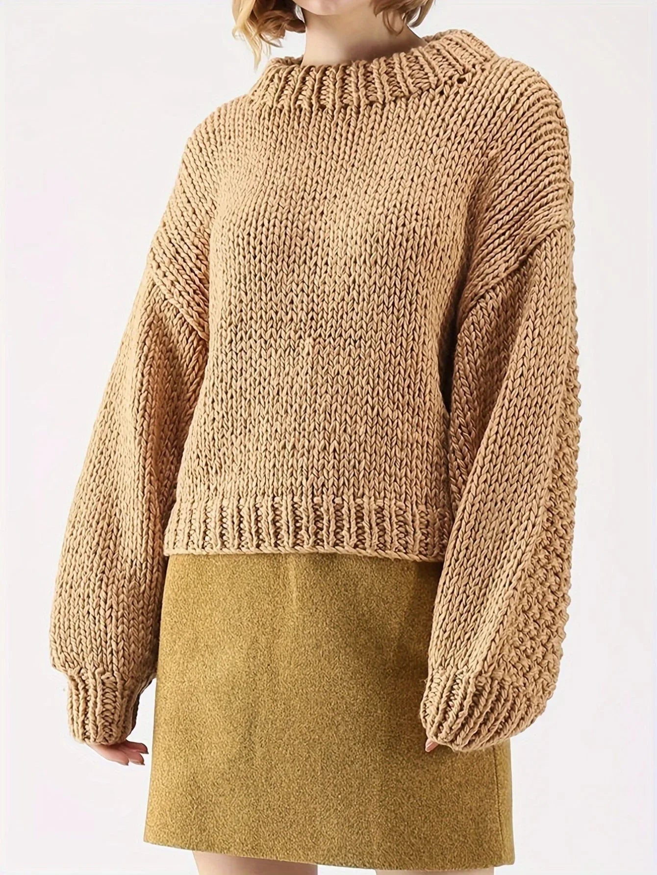 Woman wearing a tan chunky knit sweater with balloon sleeves and a mock neckline, paired with a mustard yellow skirt.