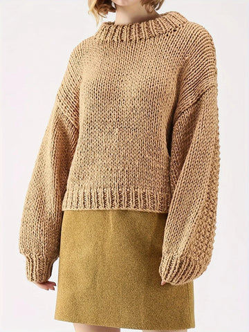 Woman wearing a tan chunky knit sweater with balloon sleeves and a mock neckline, paired with a mustard yellow skirt.
