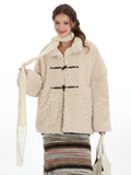 Woman wearing a cream fleece toggle coat and white scarf, holding a white tote bag