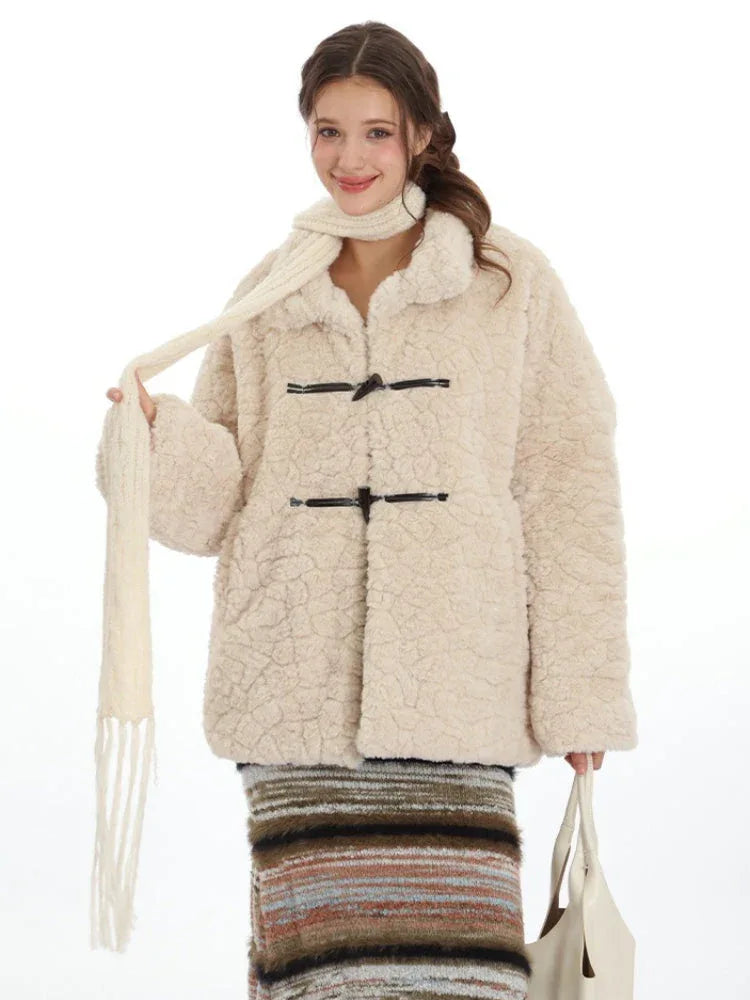 Woman wearing a cream fleece toggle coat and white scarf, holding a white tote bag