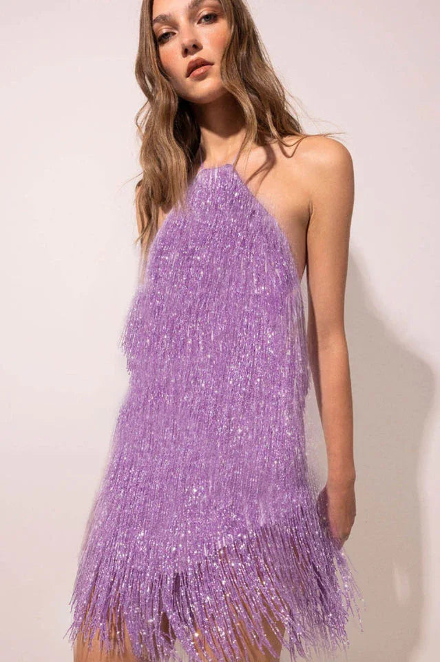 Close-up of a woman wearing a purple sequined fringe mini dress with a halter neckline.