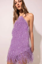Close-up of a woman wearing a purple sequined fringe mini dress with a halter neckline.