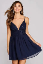 Woman wearing a navy blue sequin and chiffon party dress with a v-neck and spaghetti straps.