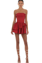 Woman wearing a red strapless tiered ruffled mini dress with a lace-up back, full body view
