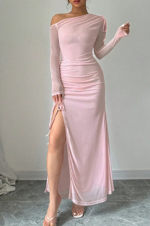 Close-up of a woman's legs and the side slit of a pink ruched maxi dress.