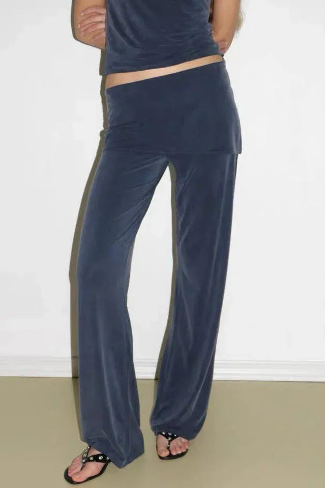 Close-up of navy velour wide leg pants with a flared hem and a high rise elastic waistband, worn with sandals.