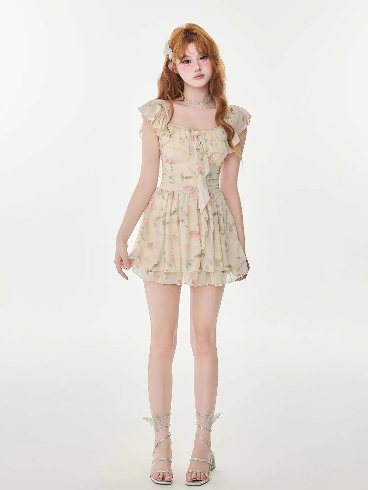 Full body shot of a woman wearing a cream floral print chiffon mini dress with ruffle trim.
