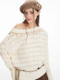 Detailed view of the neckline and upper chest area of a cream-colored off-the-shoulder knit sweater featuring a diamond pattern and decorative trim with small embellishments.