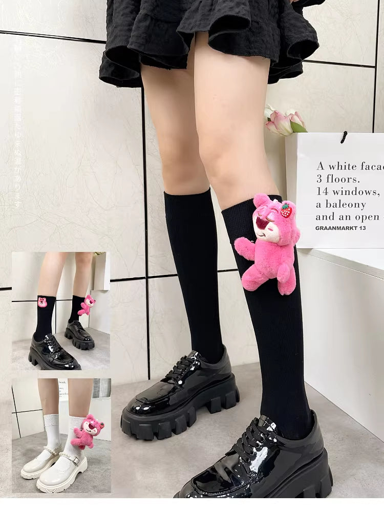 Side view of black knee-high socks with a pink plush bear charm.