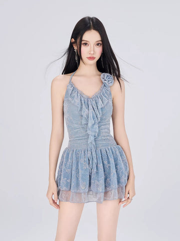 Model wearing a light blue textured lace halter dress with floral applique and tiered hem