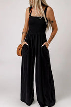 Woman wearing a black wide leg jumpsuit with a smocked bodice and square neckline