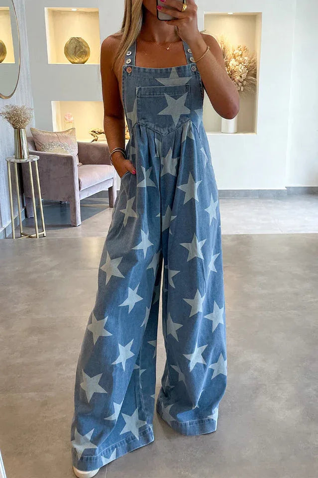 Front view of a woman in a star-print denim jumpsuit with adjustable button straps.