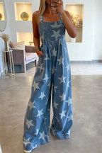Front view of a woman in a star-print denim jumpsuit with adjustable button straps.