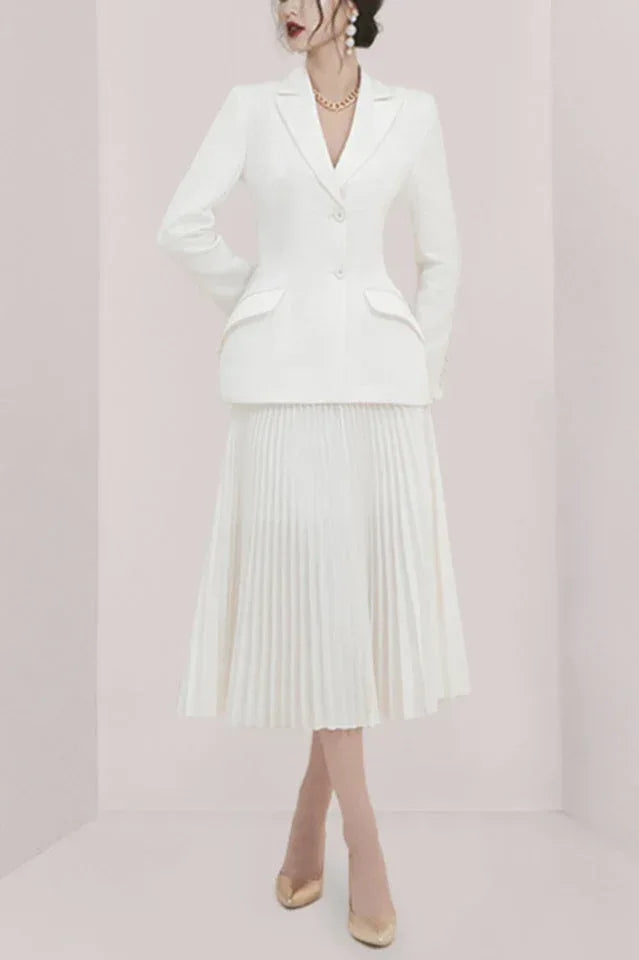 Woman wearing a white tailored blazer and a white pleated midi skirt.