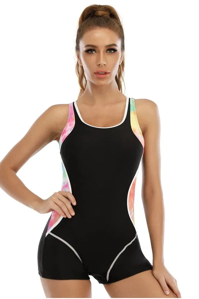 Woman wearing a black one-piece swimsuit with pink, yellow, and blue tie-dye side panels and white piping