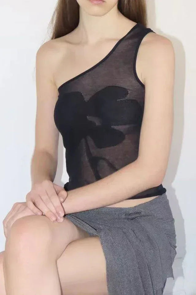 Model sitting in a black asymmetric one shoulder top and grey skirt