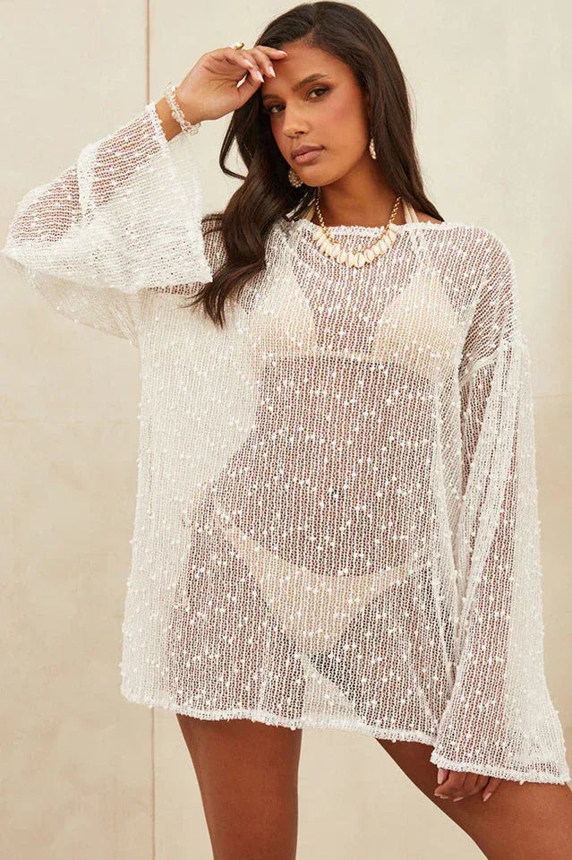 Front view of a woman in a white sheer knit tunic with long bell sleeves.