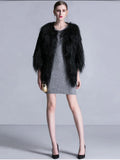 Woman wearing a black faux fur cropped jacket over a grey knit dress