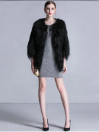 Woman wearing a black faux fur cropped jacket over a grey knit dress
