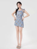 Full body shot of a woman in a blue plaid A-line dress with tie shoulder straps