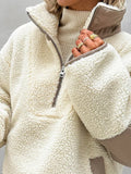 Detail of the sleeve cuff and contrast trim on a cream sherpa fleece pullover.