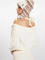 Back view of a white off-the-shoulder cable knit sweater with tie detail