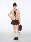 Full body shot of a woman in a light pink cardigan, brown skirt, white socks, and loafers