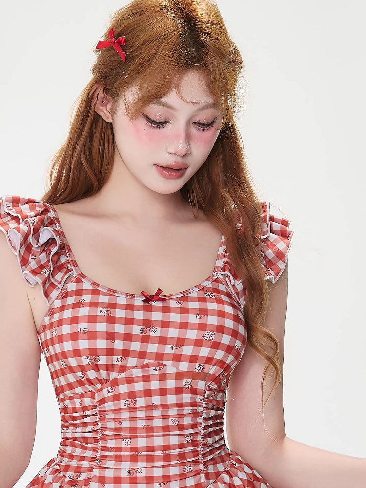 Woman wearing a red and white gingham dress with ruffled sleeves and a bow accent