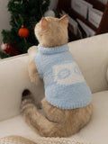Rear view of a cat wearing a light blue fluffy knit pet vest with a mock neck and a white graphic detail on the back.