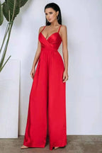 Woman wearing a red satin jumpsuit with wide legs and spaghetti straps
