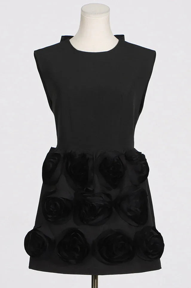 Close-up of a black mini dress with floral embellishments and a high neckline on a mannequin.