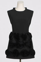 Close-up of a black mini dress with floral embellishments and a high neckline on a mannequin.