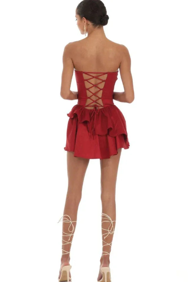 Woman wearing a red strapless tiered ruffled mini dress with a lace-up back, back view