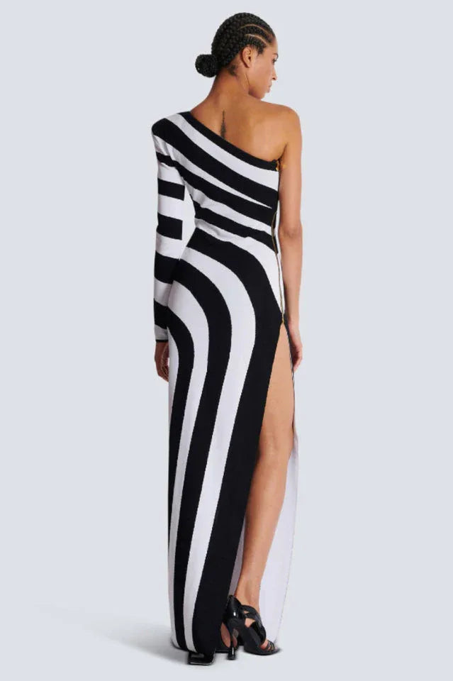 Back view of a woman in a black and white one-shoulder knit gown with a high slit