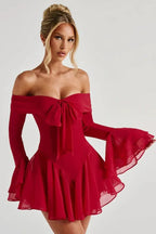 Woman wearing a red off-the-shoulder dress with flared sleeves and a bow detail